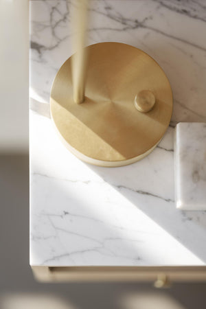 Guldfarad rund lampa i mässing på vit marmorbänkskiva med minimalistisk design
