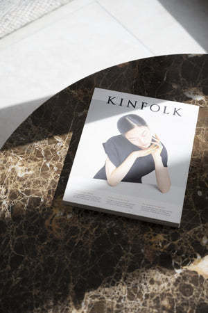 Kinfolk magasin liggande på ett marmorbord med kvinna i svartvitt på omslaget