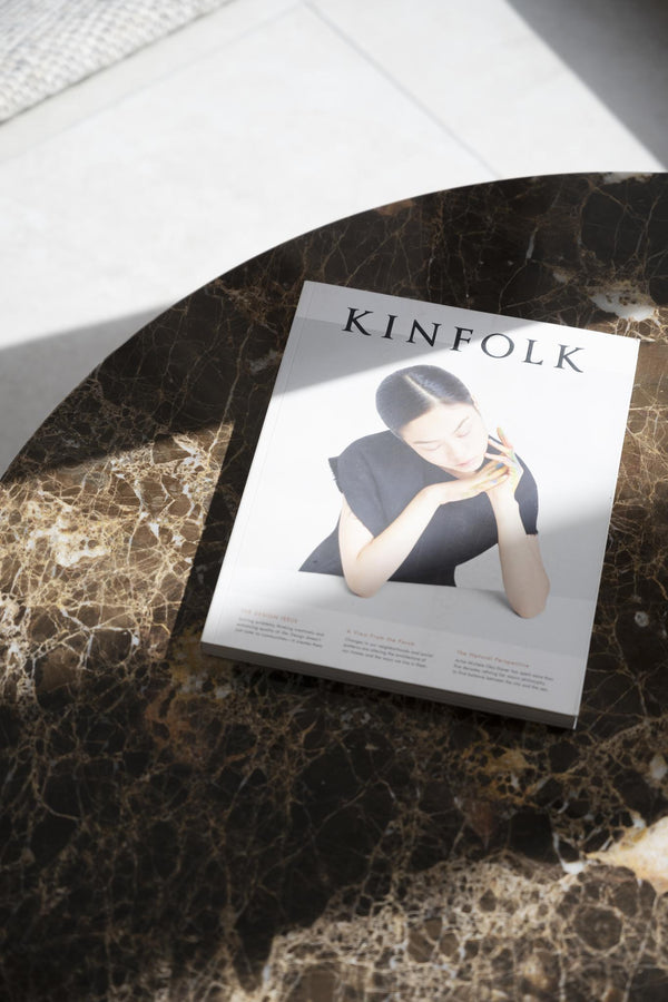 Kinfolk magasin liggande på ett marmorbord med kvinna i svartvitt på omslaget