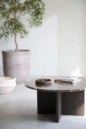 Runt soffbord med marmorskiva och svart träfot, dekorerat med böcker och skål, bredvid krukväxt