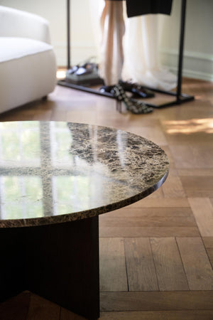 Runt marmorbord med grå-beige yta och polerad finish i modernt vardagsrum med trägolv