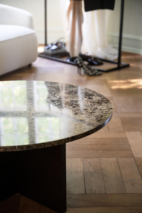 Runt marmorbord med grå-beige yta och polerad finish i modernt vardagsrum med trägolv