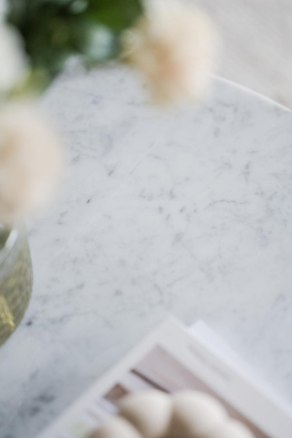 Handskriven skiss och teckningar på vitt papper bredvid pastellfärgade materialprover och gröna växter