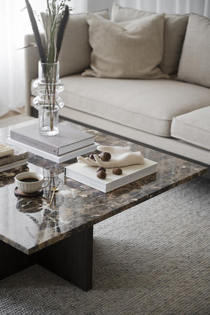 Modernt vardagsrum med marmorsoffbord, beige soffa och minimalistisk inredning i neutrala toner