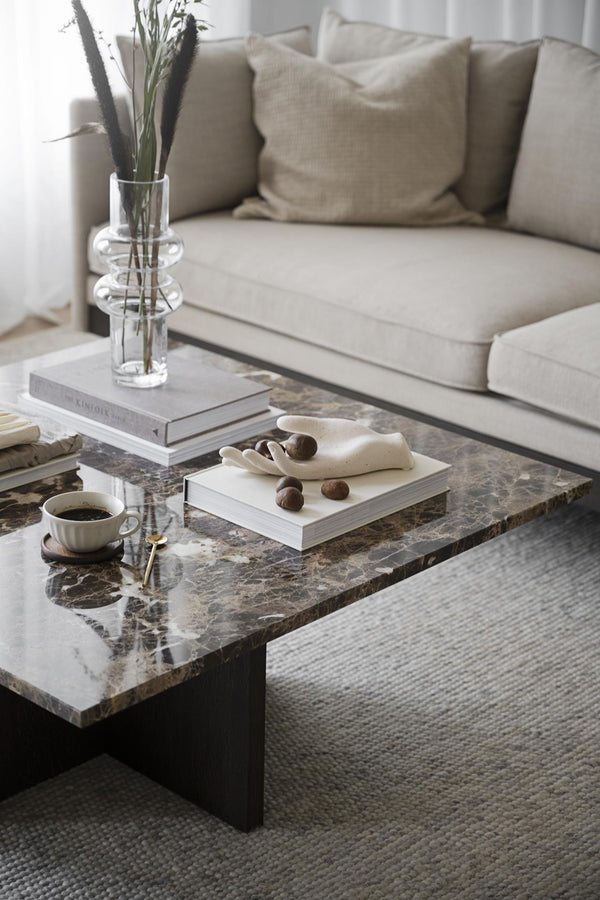 Modernt vardagsrum med marmorsoffbord, beige soffa och minimalistisk inredning i neutrala toner