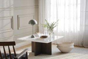 Soffbord med vit marmorskiva och mörkbrun träfot i vardagsrum med lampa och dekoration