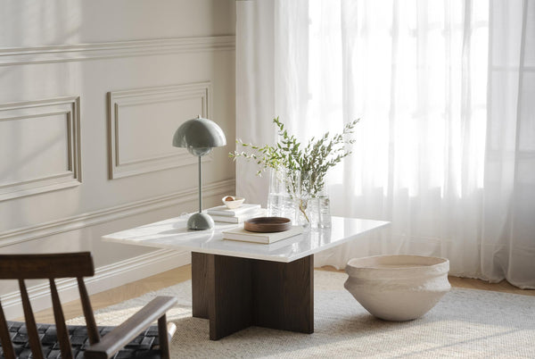 Soffbord med vit marmorskiva och mörkbrun träfot i vardagsrum med lampa och dekoration