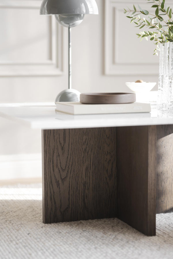 Soffbord med vit marmor och mörkt trä, dekorerat med lampa och böcker i modernt vardagsrum