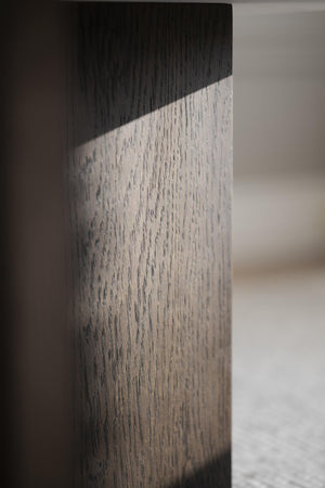 Närbild på möbelben i tvåfärgat trä med svart topp och ljust grått skaft med synlig trästruktur