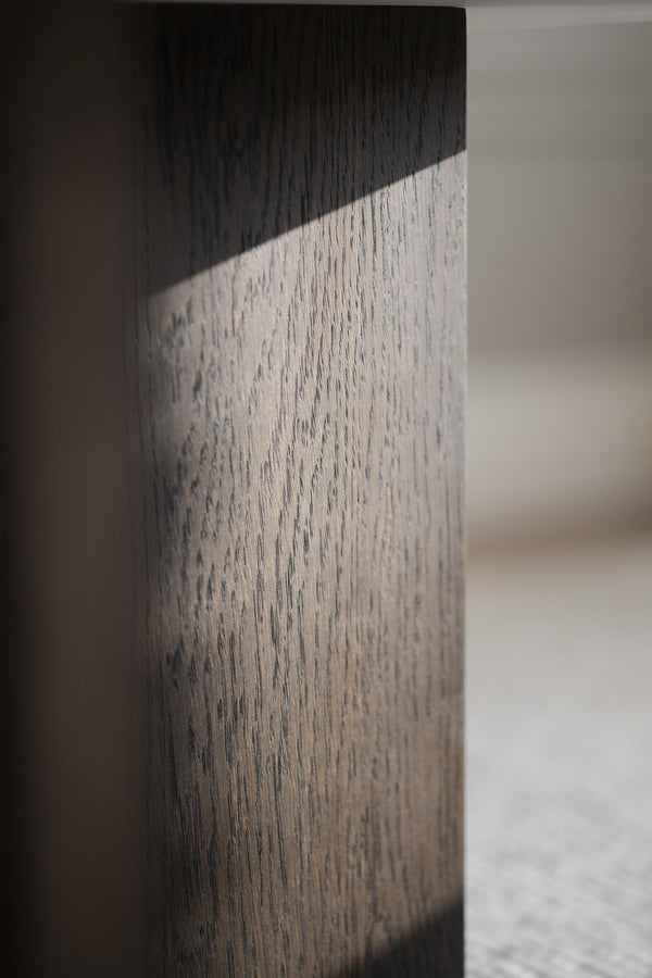 Närbild på möbelben i tvåfärgat trä med svart topp och ljust grått skaft med synlig trästruktur