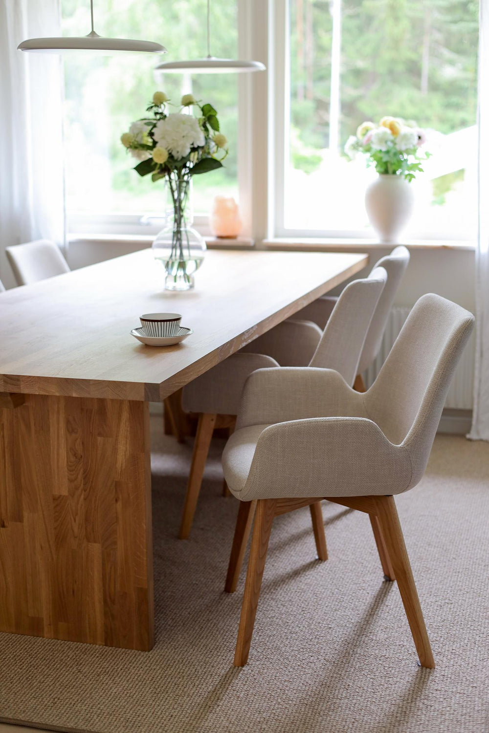 Beige stoppad stol med armstöd och träben i ekfärg, modern skandinavisk design