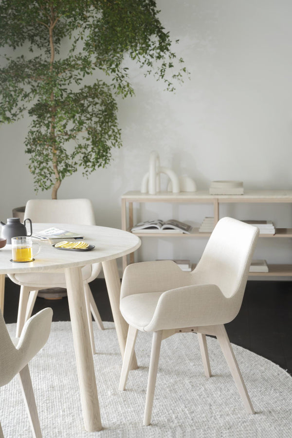 Ljus matgrupp i skandinavisk stil med runda bordet och beiga stolar med armstöd i minimalistisk matsal