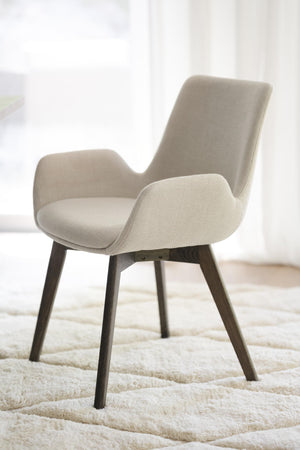 Beige stoppad stol med armstöd och mörka träben på ljus matta i modernt rum