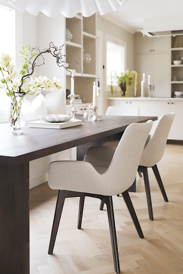 Ljus matplats med mörkbrun matbord, beige stolar och vita blommor i skandinavisk stil