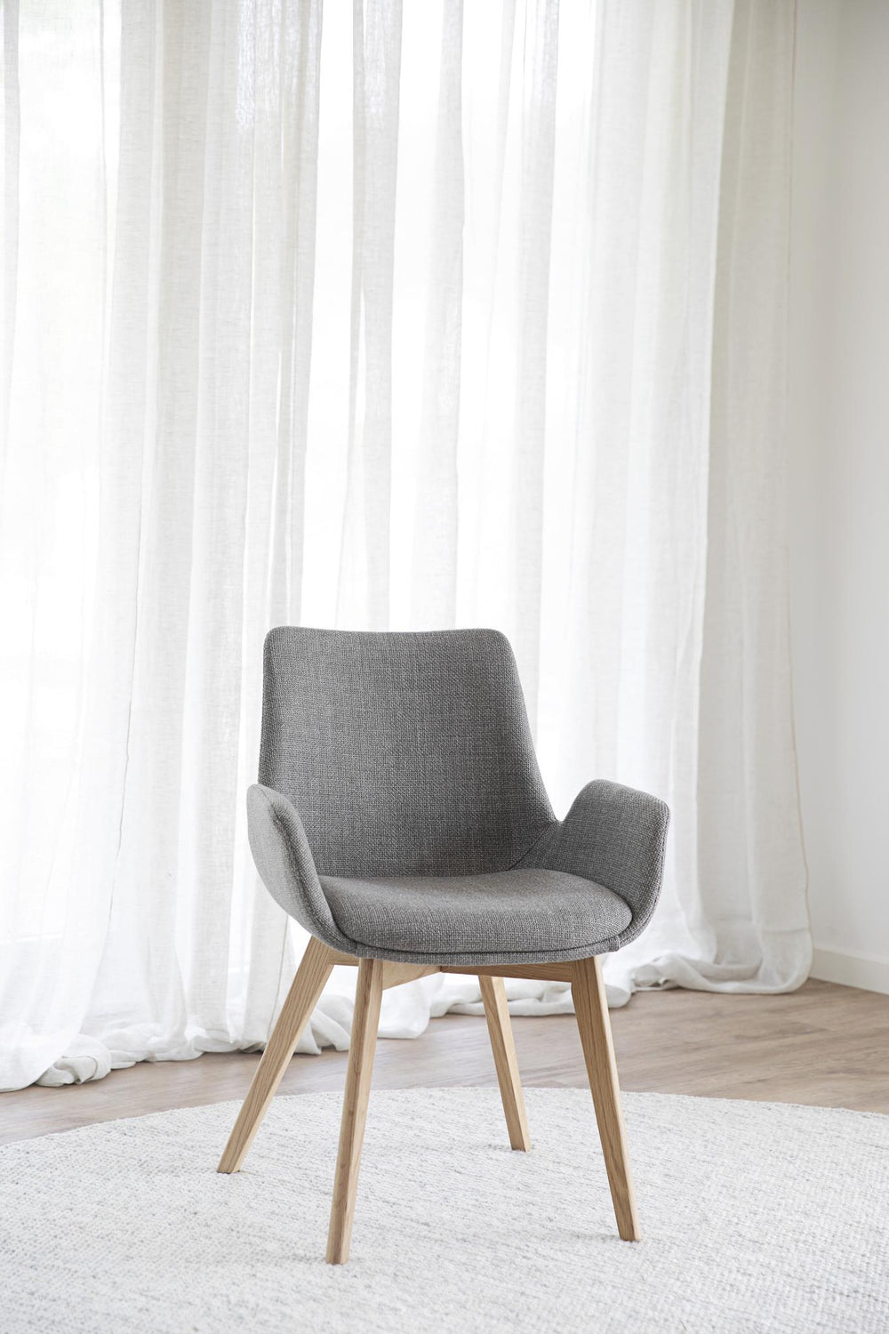 Grå fåtölj med armstöd och träben i ek, modern skandinavisk design
