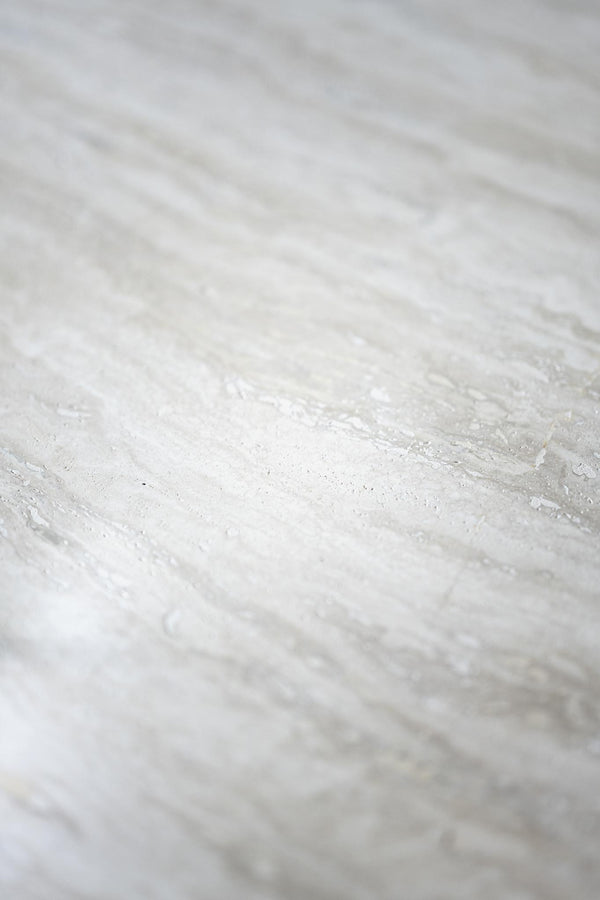 Närbild av vit marmor med grå ådring och naturlig stenmönster, lämplig för bänkskiva eller kakel
