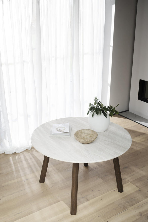 Runt soffbord med vit marmorskiva och träben i modernt vardagsrum med vita gardiner