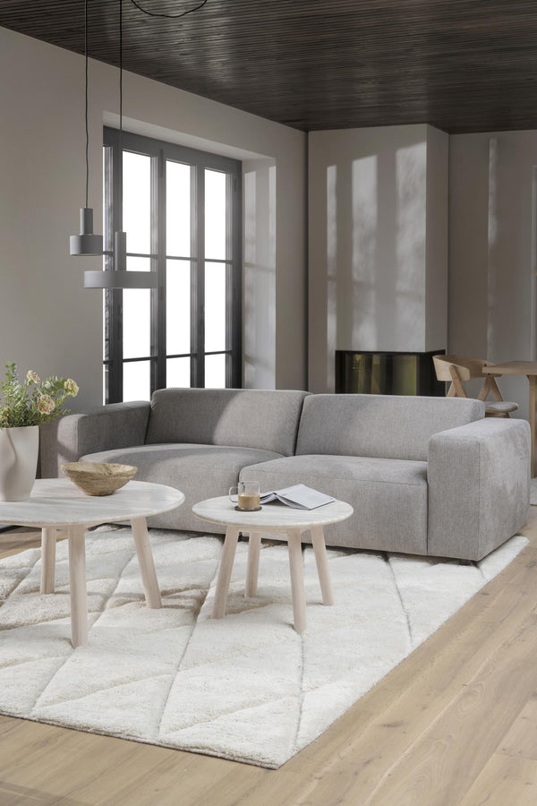 Grå soffa med ljusa soffbord i modern vardagsrumsmiljö med vit matta och mörkt tak