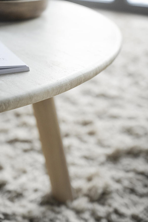 Vit runt soffbord i marmor med träben på mönstrad matta