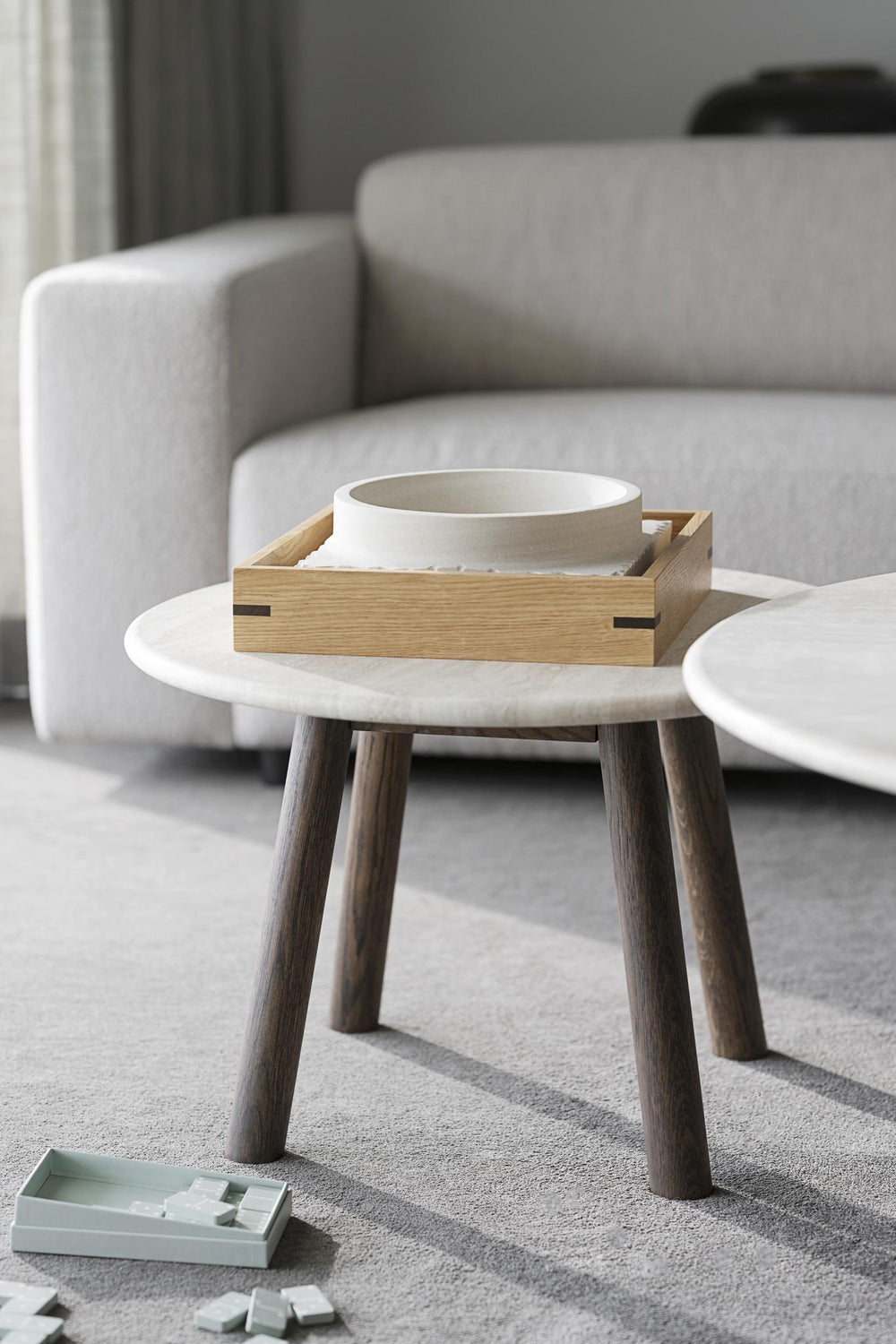 Runt soffbord med ljus marmorskiva och mörka träben i modern skandinavisk design