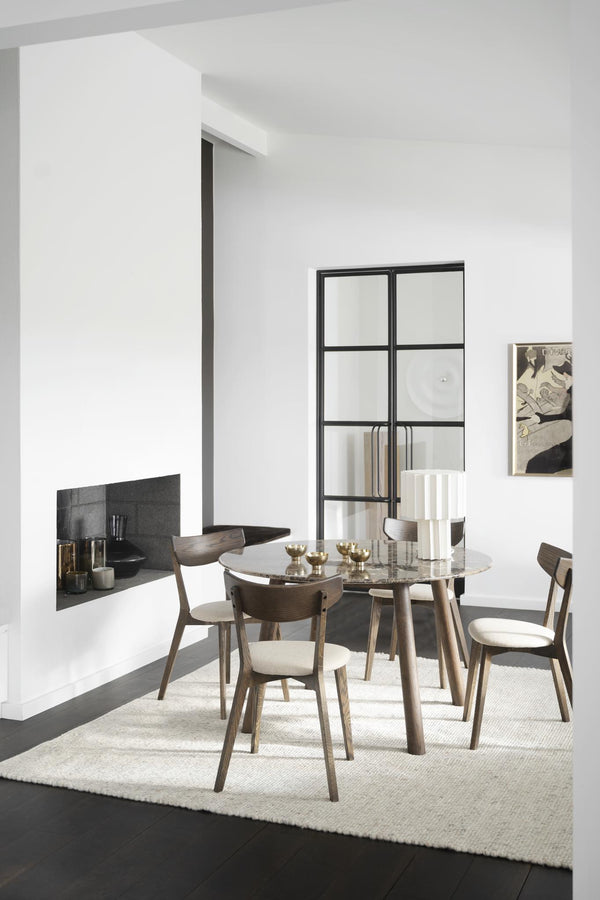Rund matbord i trä med stolar i modern matsal med vit matta och svarta detaljer