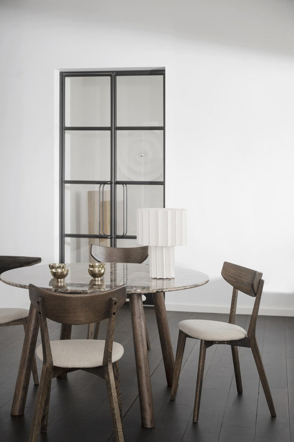 Runt matbord i marmor med träben och stolar i skandinavisk design, vit skulptur och glaskåpa som dekoration