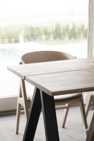 Matbord i ljust trä med svarta A-formade ben och moderna stolar i skandinavisk design