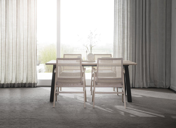 Matgrupp med ljust trä och rotting i minimalistisk matsal med stora fönster och gardinuppsättning