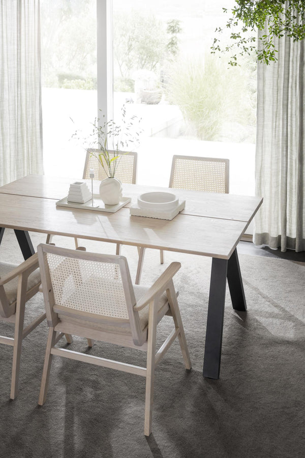 Ljus matgrupp med rotting-stolar och träbord vid panoramafönster i skandinavisk stil