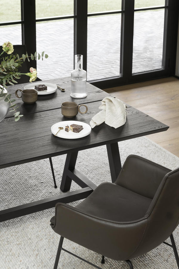 Matbord i mörk ek med stolar i läder, dukat med koppar och tallrikar vid fönster med vattenvy