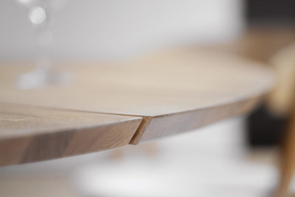 Närbild på träskiva med synlig spricka eller fogning i ljust trä, ofokuserad bakgrund