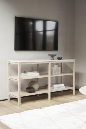 Ljust TV-bänk i trä med öppna hyllor, dekorerad med böcker och keramik under väggmonterad tv