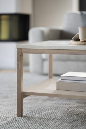 Soffbord i ljust trä med marmortop och hylla, standing på ljus matta i modernt vardagsrum