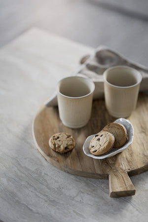Träbricka med två kaffemuggar och kakor på vit bordsskiva - rustik serveringsbricka för fika