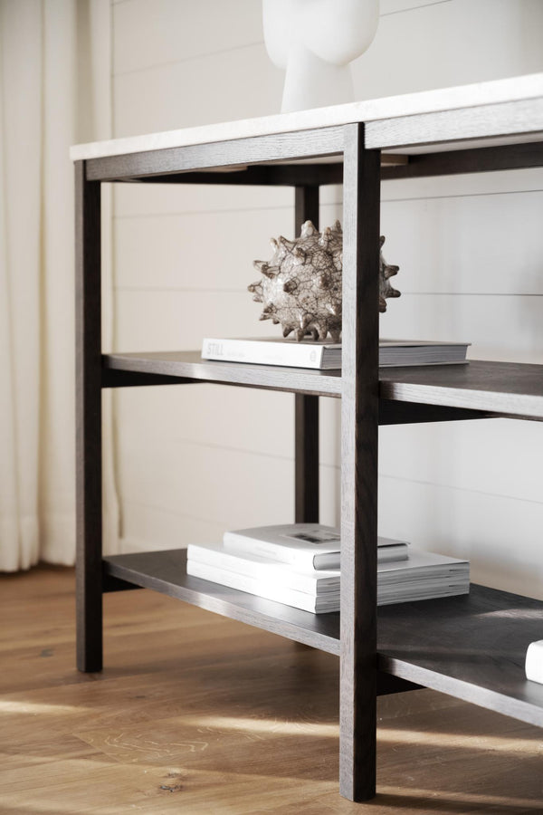 Modern hylla i svart och grått med böcker och dekorativt föremål, närbild på hyllplan och ben