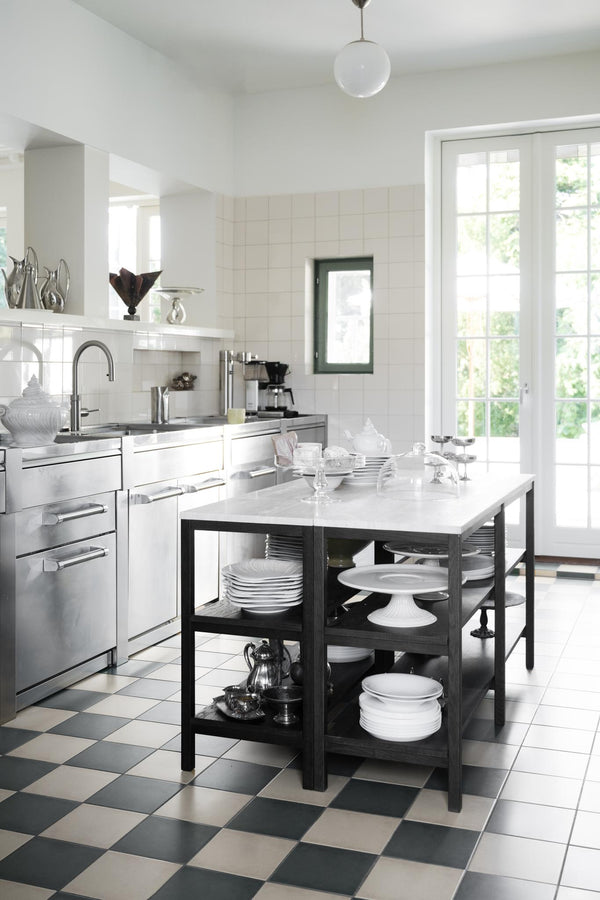 Modernt kök med vit köksö i svart metallram, schackrutigt golv och franska altandörrar