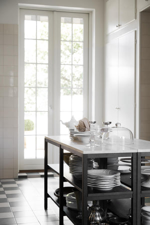 Köksö med marmorbänkskiva och svart stomme, öppen förvaring med tallrikar och porslin i vitt kök