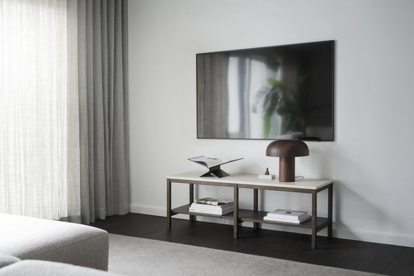 Minimalistiskt TV-bänk i vit och grå metall med hylla, mushroom-lampa och väggmonterad TV i modernt vardagsrum