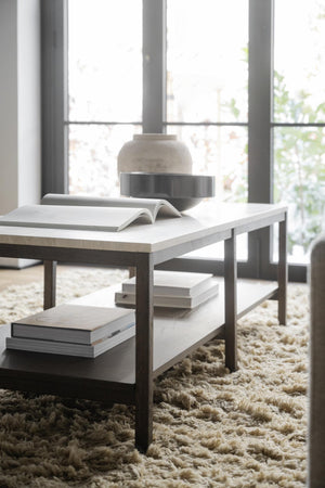 Soffbord i vit marmor och metall med böcker på fluffig beige matta framför fönster