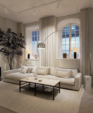 Beige modulsoffa med schäslong i ljust vardagsrum med högt i tak och stora fönster med bågar