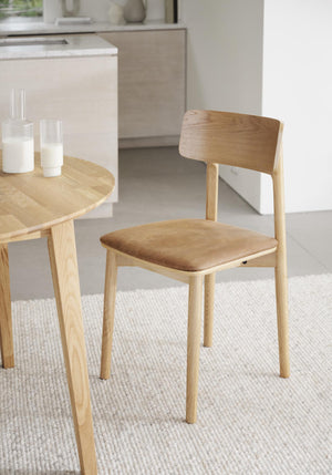 Ljus trämatstol med stoppad sits i beige tyg, modern skandinavisk design med rundad rygg