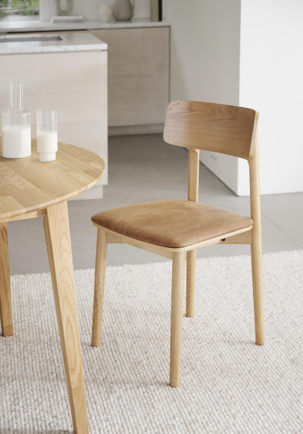 Ljus trämatstol med stoppad sits i beige tyg, modern skandinavisk design med rundad rygg