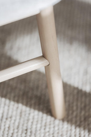 Närbild på ljust trämöbel med synlig trästruktur och robust konstruktion på vävd textilmatta