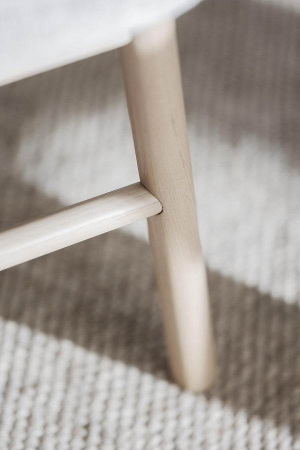 Närbild på ljust trämöbel med synlig trästruktur och robust konstruktion på vävd textilmatta