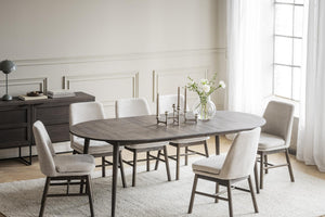 Matbord i oval form med sex stoppade stolar i beige tyg, modern skandinavisk design för matsal