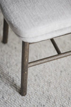 Närbild på stolsben i mörkbetsad ek med genomgående tvärsprint på ljusgrå matta