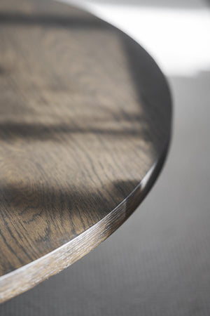 Närbild av träbordsskiva med synlig årsringsstruktur och naturlig mörkbrun yta med svart kant