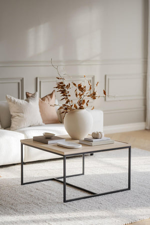 Soffbord med metallstativ och träskiva, dekorerat med vit vas med torkade grenar och böcker i neutral stil