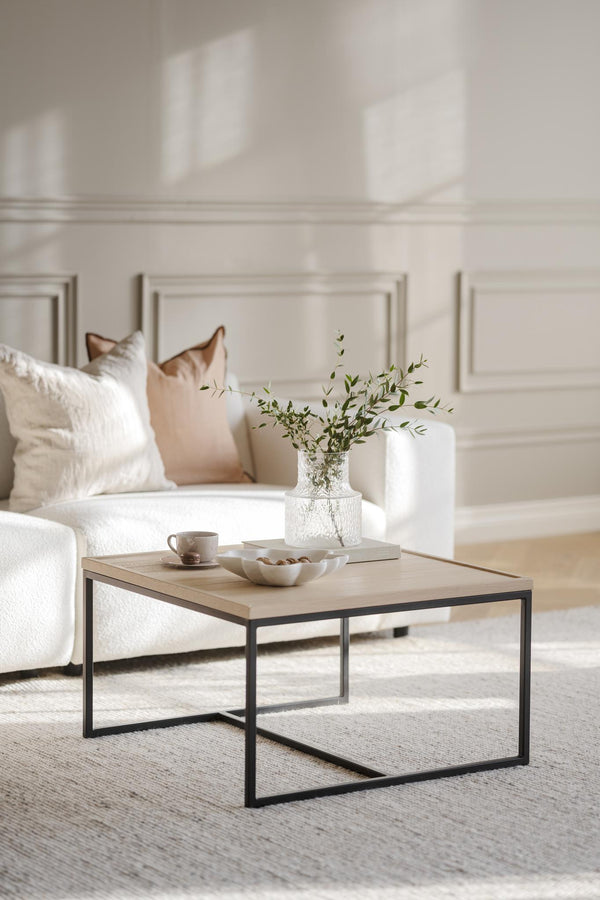 Soffbord i ljust trä med svart metallram, dekorerat med vas, kopp och skål i ljust vardagsrum