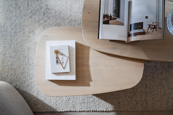 Ovalt träsoffbord med böcker och dekoration på ljus matta i skandinavisk stil